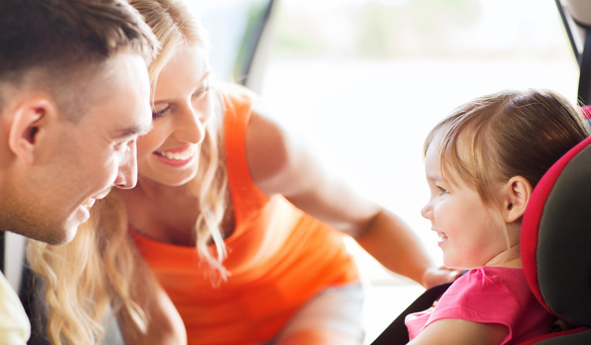 married couple smiling at their daughter while sitting her at the car chair chesapeake va